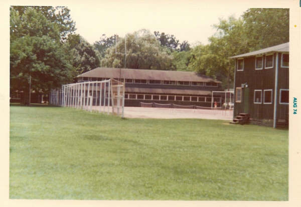 Steps lead to new radio studio in rear of Woodcraft Building; original studio had been on second floor, in the front of the building. Tennis courts and Dining Hall can be seen in the background. Later, a weather station shelter was mounted on edge of the fence (closest to the radio studio) bordering the tennis courts.